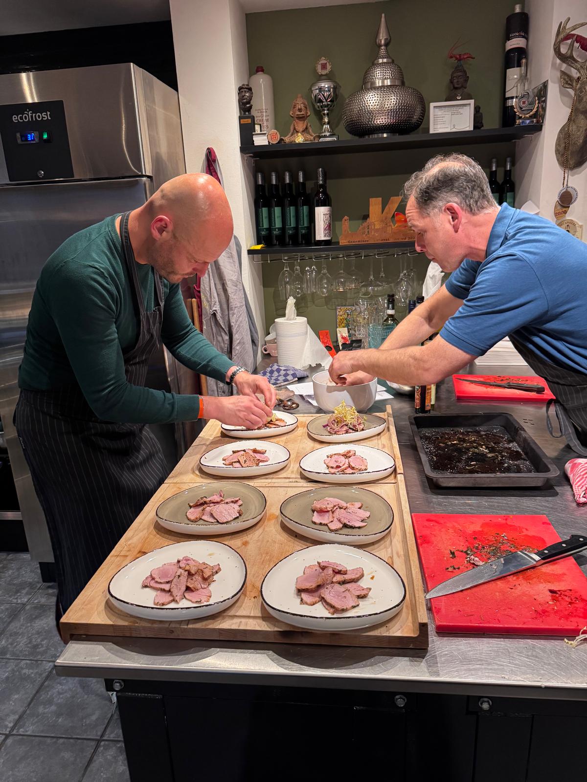 Twee kels werken zij aan zij aan een rij borden.