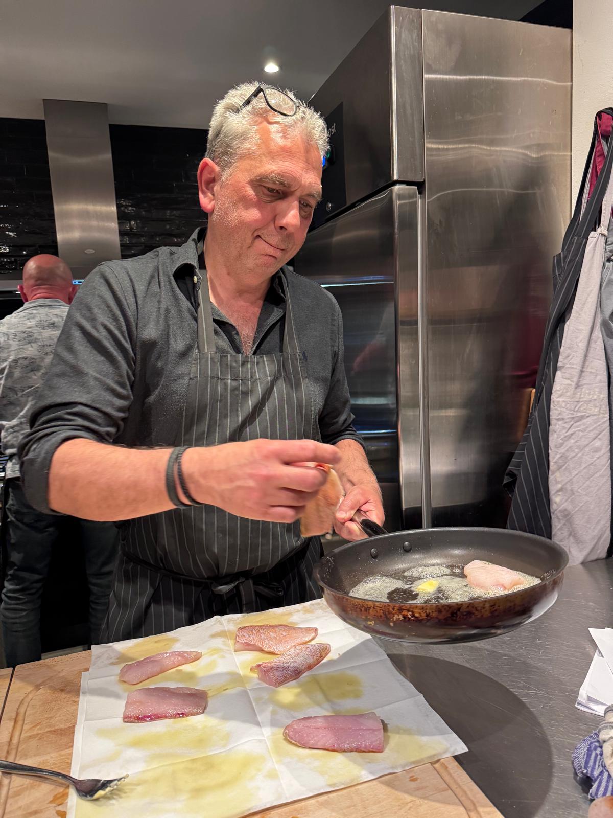 Een kel laat plakken vlees in een pan zakken.