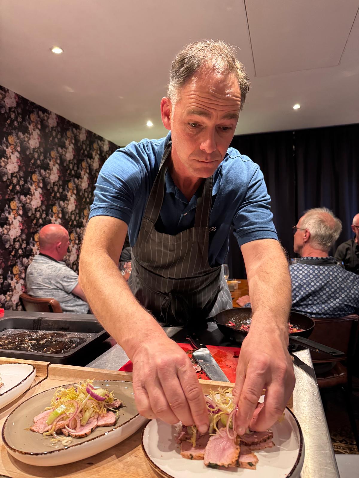 Een kel garneert een bord met fijne hand.
