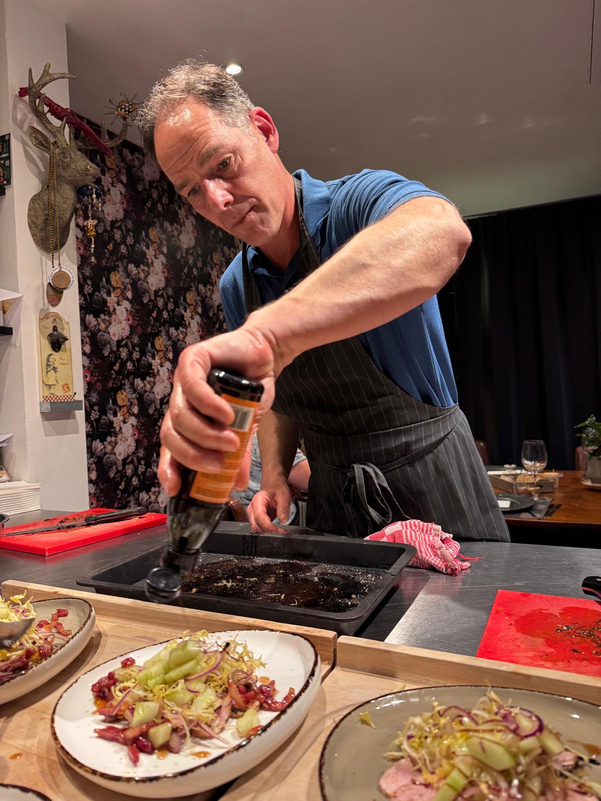 Een kel maalt versgemalen peper boven de saus.